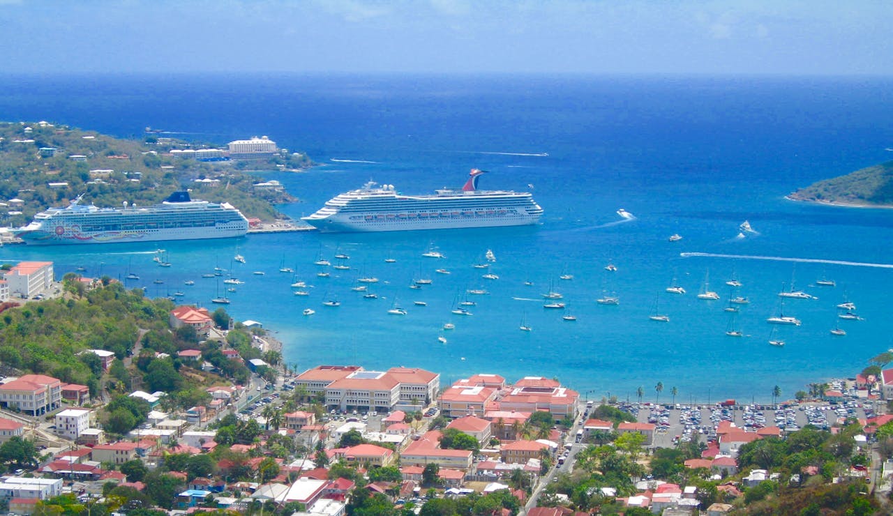 services-04 Scenic aerial view of a tropical harbor with cruise ships and sailboats in clear blue waters.